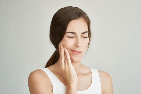 female holds jaw muscle from painful TMJ dysfunction